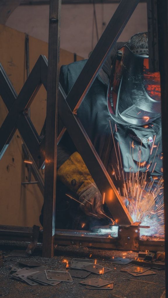 Elmiron certified welder — precision and safety in European industrial projects A welder wearing a mask in a workshop, creating sparks while welding metal.